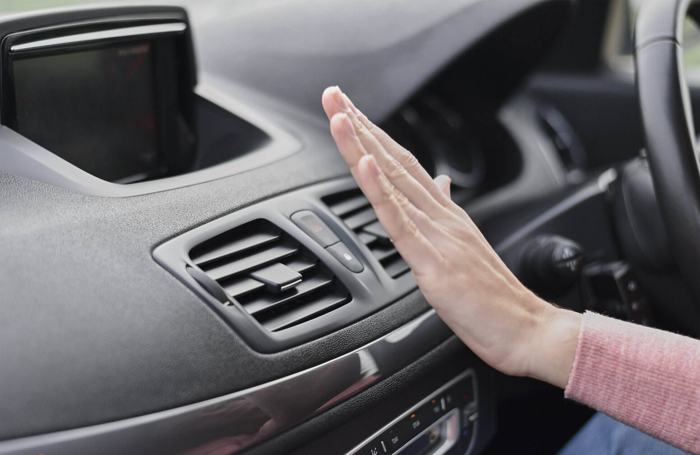 Woman hand on air conditioner ventilation grille in the car. Cli Rekomendasi Tempat Service AC Mobil